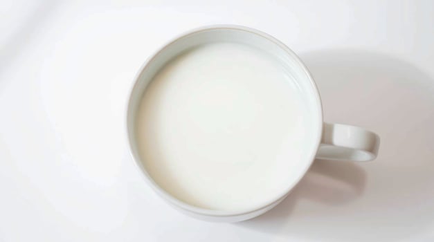 A white cup of milk on a white surface photo