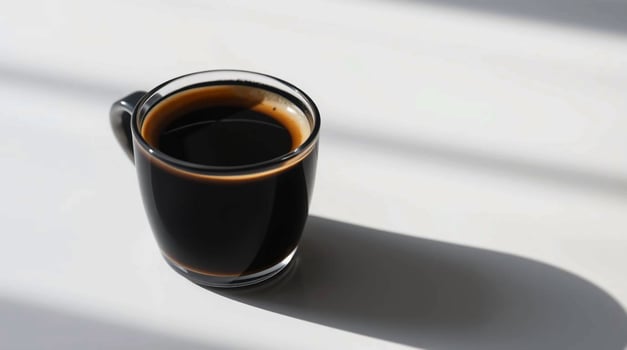 A cup of black coffee on a white surface photo