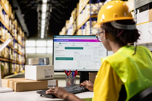 Black woman working in logistics center with tracking info on computer software, updating the route and other shipment details in real time. Cargo parcel status for e-commerce orders. photo