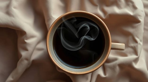 Overhead View of Steaming Coffee in a Mug on Beige Fabric Beverages photo