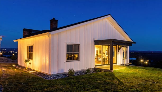 A small white house with a porch lit up at night photo