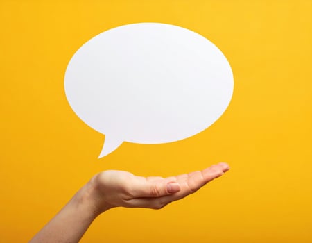 Hand is open and gesturing towards blank speech bubble against bright yellow background, symbolizing communication and expression. This evokes creativity and interaction photo