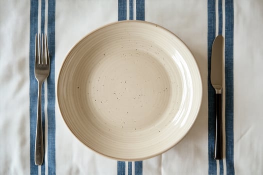 Empty plate, fork, knife on striped tablecloth. photo