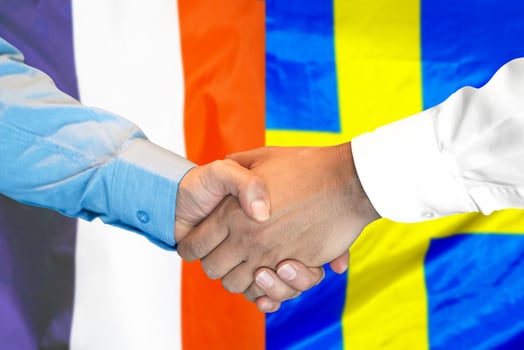 handshake on France and Sweden flag background. photo