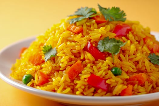 A plate of yellow rice with vegetables and herbs photo