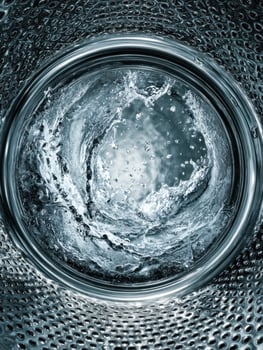 Dynamic whirlpool of water swirling inside a modern washing machine drum photo