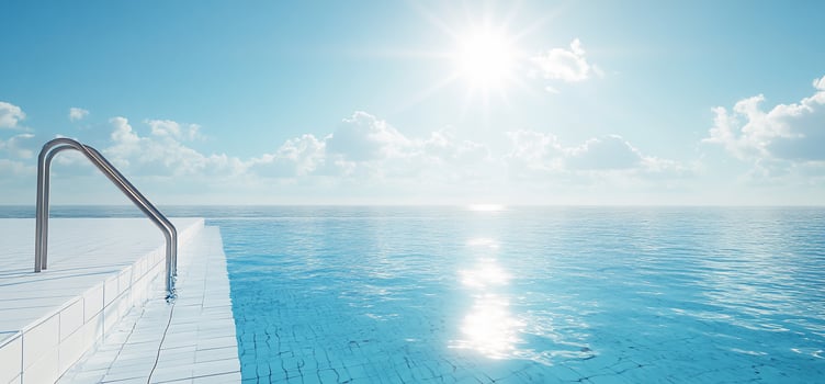 Infinity pool steps leading to a bright blue ocean under a sunny sky. photo