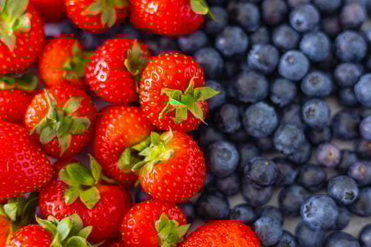 Top view of freshly picked strawberries and blueberries side by side, showcasing vibrant colors, natural sweetness and antioxidant-rich fruits. Healthy summer snacks and balanced nutrition photo