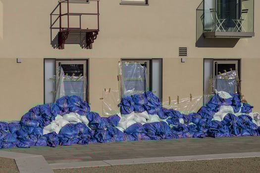 Flood protection with blue and white sandbags and plastic sheeting taped over windows of a building photo