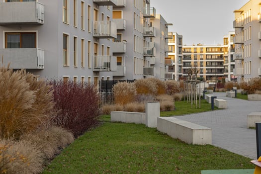Modern residential courtyard with ornamental grasses, shrubs, young trees and walkways surrounded by contemporary apartment buildings. Urban landscaping, eco-friendly design and sustainable living photo