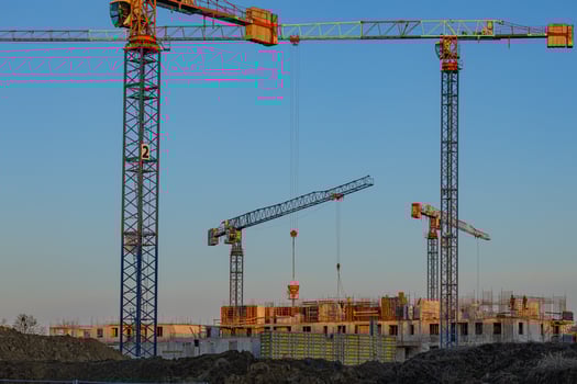 Wroclaw, Poland, December 23, 2024. Tower cranes at a construction site during sunset with workers and unfinished buildings. Urban development and industrial machinery photo