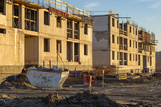 Construction site of modern residential buildings under development at sunset with scaffolding, construction materials, and equipment in foreground, reflecting progress and urban infrastructure growth photo