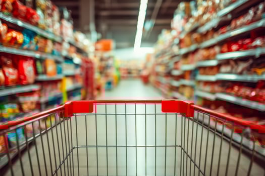 View from an empty shopping cart in a grocery store aisle with blurred shelves filled with products photo