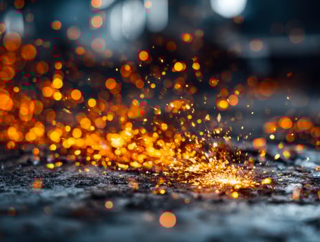 Sparks and fiery particles illuminating a dark surface in a close-up shot photo