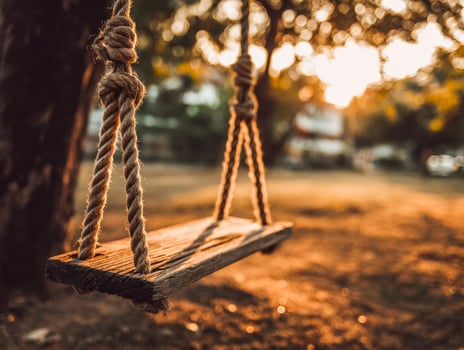Wooden outdoor swing on a sunlit playground at sunset photo