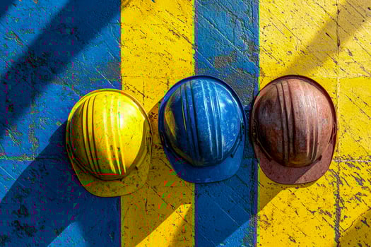 Three safety helmets on a painted yellow and blue wooden surface with shadows and scratches photo