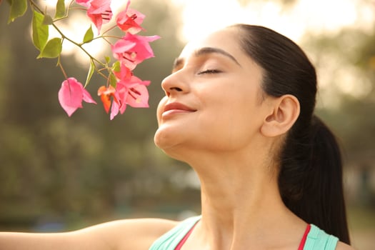 A Lovely Female Is Smelling Flowers In A Garden photo