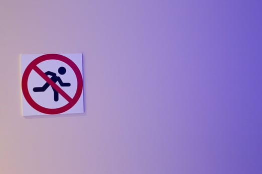 No running sign on light blue background. The symbol shows person running crossed out with red circle, enforce safety regulations in areas where running is prohibited photo