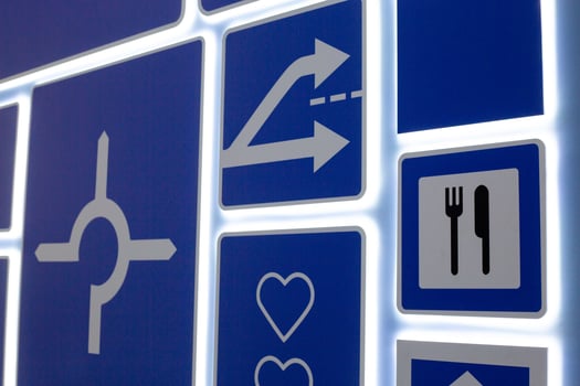 Illuminated road signs on panel, featuring symbols like arrows, roundabout and dining, aimed at teaching children road safety and traffic rules. The design highlights clear, visual instruction photo