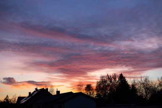Beautiful sunset over suburban rooftops with vibrant pink and purple clouds and silhouetted trees. Concept of peaceful evening, colorful sky, and residential landscape at dusk photo