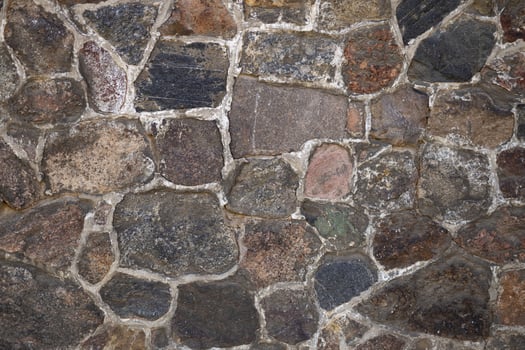 Close-up of a rustic stone wall with irregular shapes and natural texture in daylight. Concept of architecture, construction, and outdoor background photo