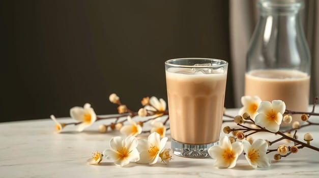 A glass of milk and a bottle of milk next to flowers photo
