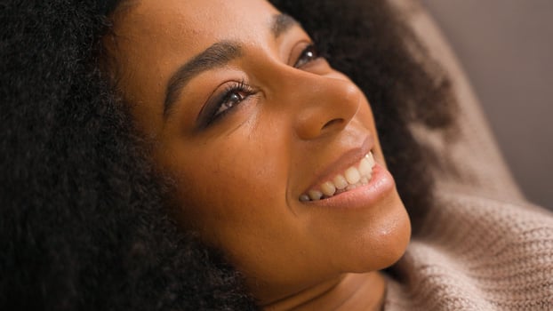 Close up African American happy smiling joyful woman beautiful young female relaxing lying on sofa cheerful positive girl homeowner resting on cozy soft couch at home dreaming enjoying break leisure photo
