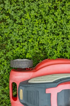 Red lawn mower on green clover field during lawn maintenance on a sunny day . Concept of garden care, landscaping and sustainable yard work photo