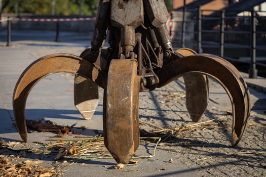 Heavy industrial claw grabber in action, collecting debris and wood on a sunny day. Concept of construction machinery, urban infrastructure maintenance, and industrial equipment photo