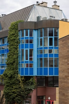 Colorful modern building with blue glass windows and ivy-covered facade blending contemporary architecture with natural elements. Concept of urban design, nature integration, and city architecture photo