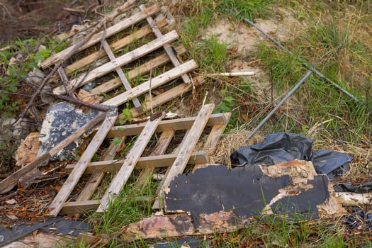 Broken wooden pallet and debris scattered on the ground in a neglected outdoor area. Concept of environmental pollution, waste management, and discarded materials photo