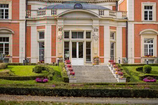 Elegant entrance of historic mansion with decorative statues and fall decorations on a bright autumn day. Concept of architectural heritage, classic design, and seasonal garden decor photo