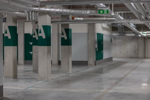 Empty underground parking garage with concrete pillars and ventilation pipes, marked with green letters and emergency exit signs. Concept of modern urban infrastructure, safety and organization photo