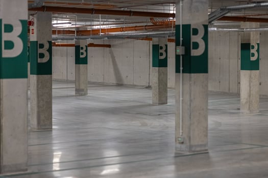 Modern, spacious and empty parking facility, featuring industrial design elements such as exposed pipes and smooth concrete flooring. Concept of urban infrastructure and city transport facilities photo