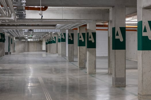 Modern underground parking lot with concrete columns, ventilation ducts, and green exit signs, featuring an organized, empty space. Concept of urban parking facilities, safety, and contemporary design photo