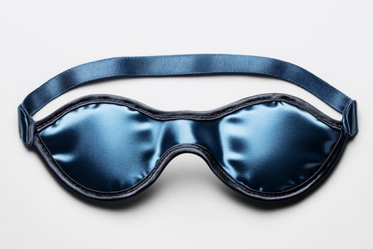 Blue satin sleep mask on white background relaxation and eye protection photo