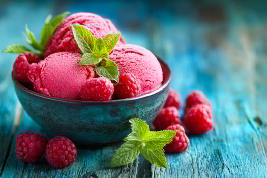 Raspberry and mint-flavored sorbet in a rustic bowl on a vibrant wooden surface photo