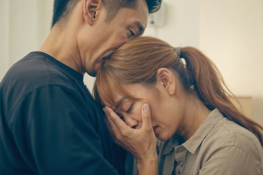 A man and woman are hugging each other while the woman is crying. The man is trying to comfort her photo