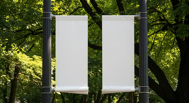 Blank vertical banners hanging on a lamp post amidst green foliage outdoor space photo