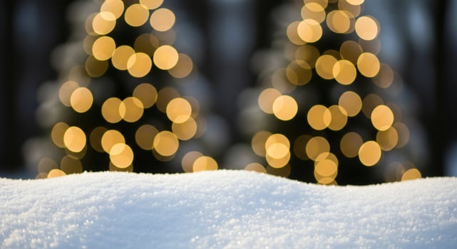 Soft white snow in the foreground with out of focus golden bokeh lights of decorated trees in the background photo
