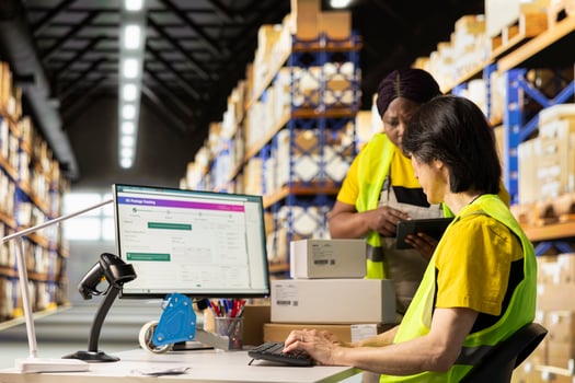 African american supervisor asking asian man about the delivery status, discussing about tracking info on a distribution software. E commerce warehouse relies on smart logistics systems. photo