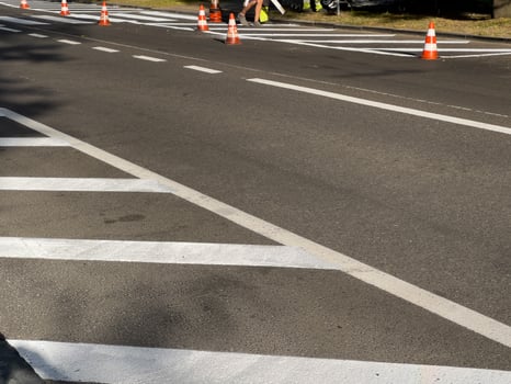 Workers manage road maintenance with traffic cones marking lane changes on a busy urban street in bright daylight photo