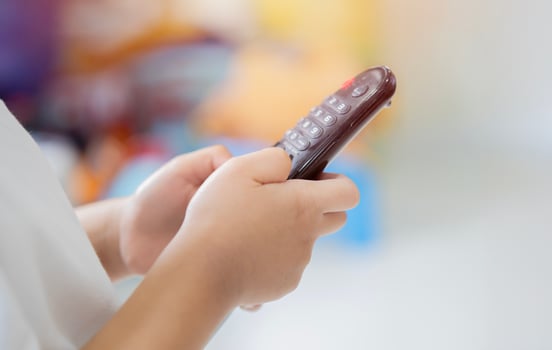 Close-up side view of a kid using television remote control. photo