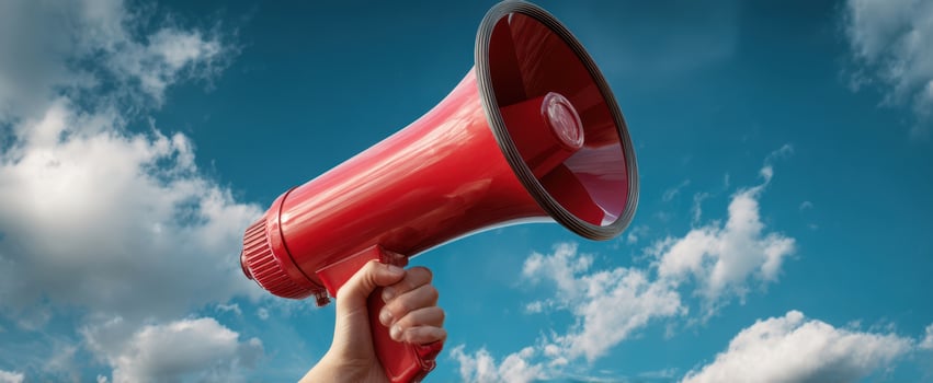 The vibrant red megaphone held high against a blue sky with clouds. photo