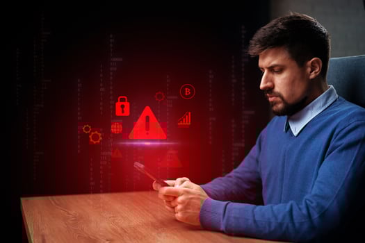 Man using smartphone while checking security alerts and data trends in a dimly lit environment photo