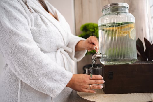 Woman pouring infused water into glass at spa photo