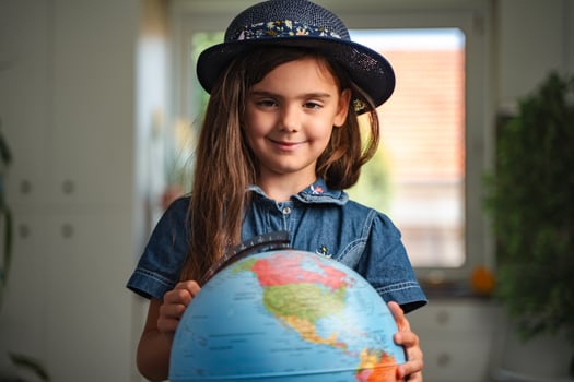 Smiling schoolgirl holding a globe, learning geography at home photo