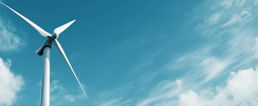 The modern wind turbine against a clear blue sky and soft clouds. photo