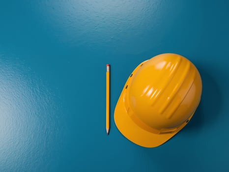 Yellow Hard Hat and Pencil on Blue Surface. Construction Planning and Safety Gear. photo