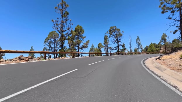 A Beautiful Winding Mountain Road Surrounded by Lush Green Trees and a Clear Blue Sky Above photo